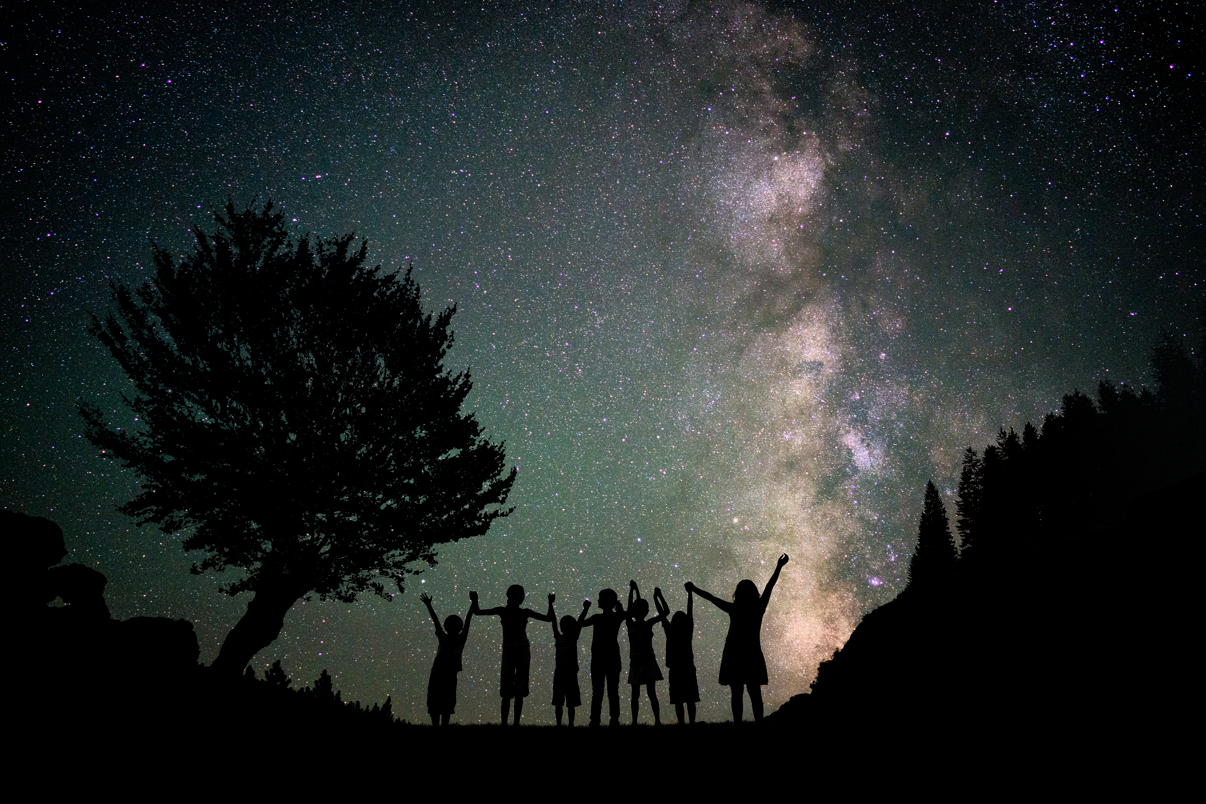 Happy kids group silhouette with Milky Way and beautiful night sky ful